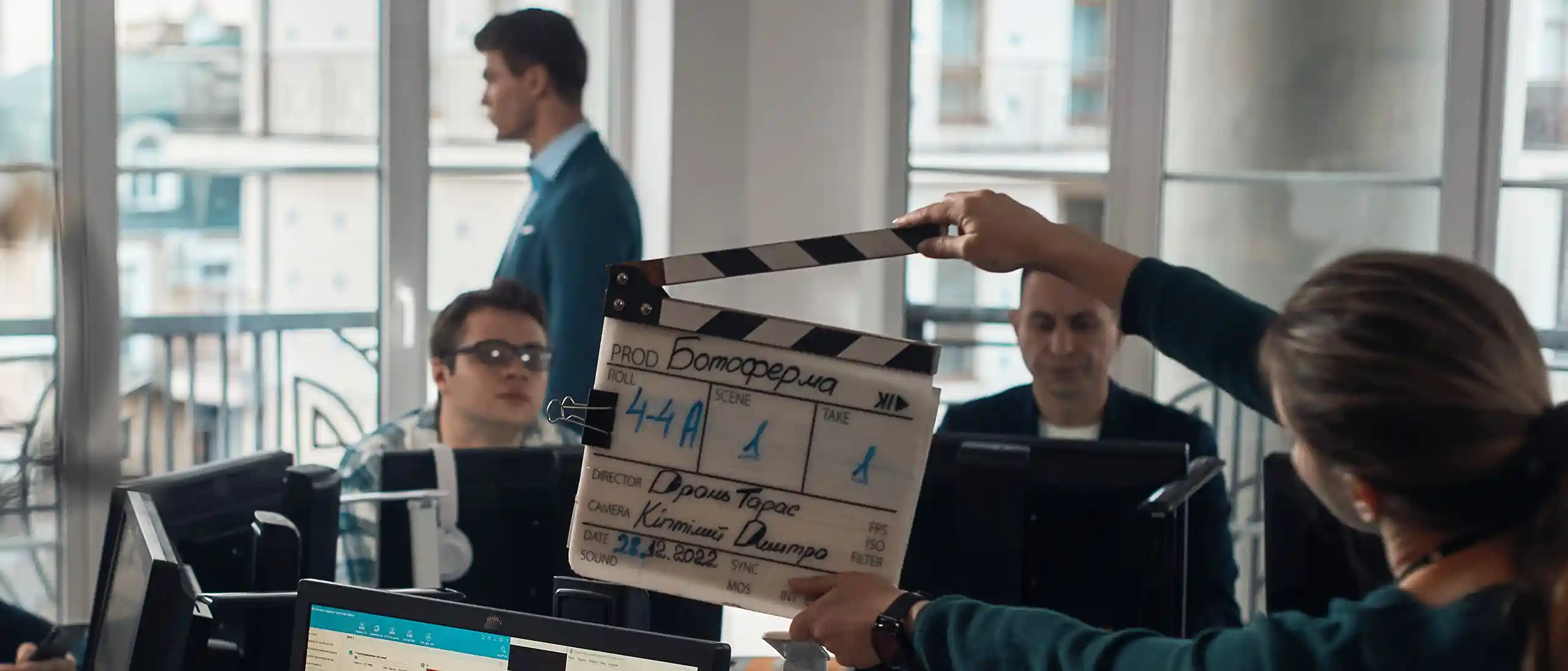 A behind-the-scenes photo from the filming of the 'Bot Farm' TV series, showcasing a clapperboard in the foreground with actors in the background.